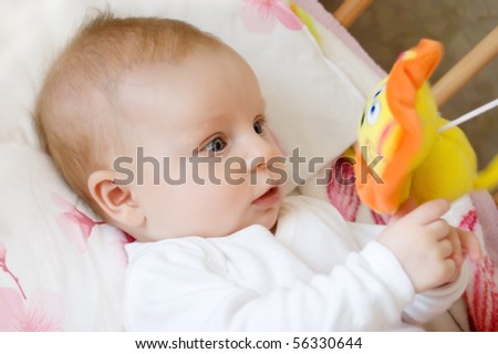 Baby lying in bed and playing with toy