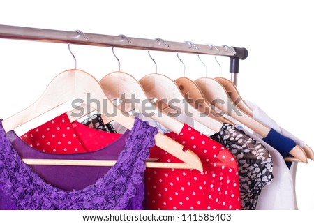 Dresses of different colors on wooden hangers over white