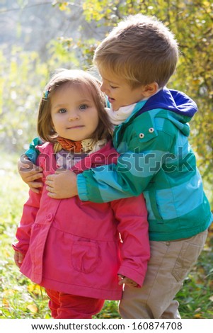 Happy brother hugging sister in autumn park