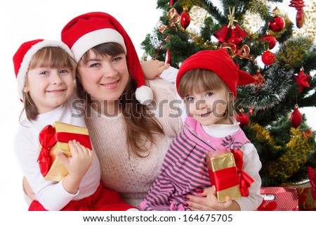 Smiling mother and two daughters under Christmas tree over white