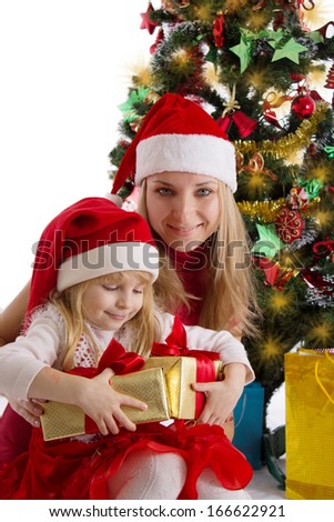 Smiling mother and little daughter with presents under Christmas tree