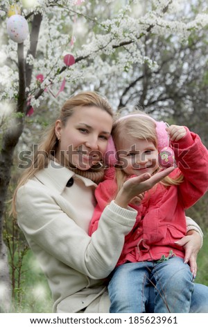 Happy mother and child with Easter eggs in spring garden