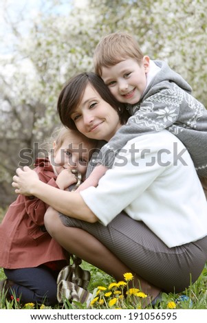 Happy mother and two children hugging among blooming garden