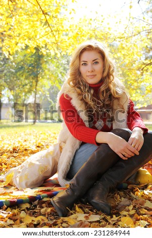 Red-headed woman in boots and fur in autumn park