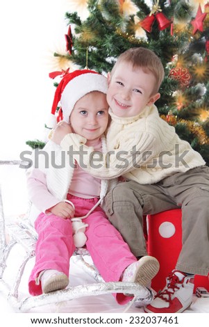 Little sister and brother hugging under Christmas tree