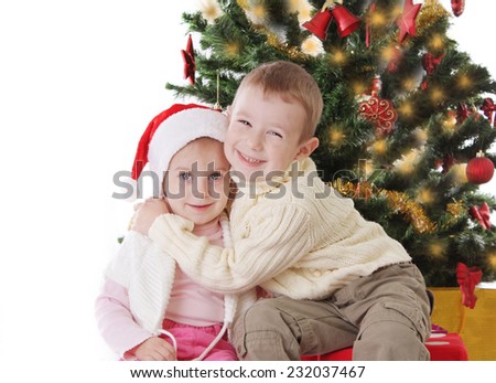 Happy sister and brother hugging under Christmas tree