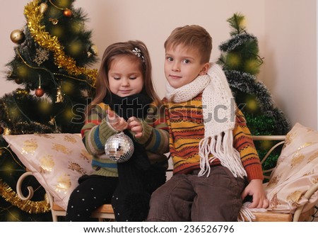 Cute sister and brother playing under golden Christmas tree