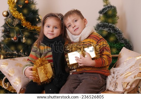 Cute sister and brother with golden presents under Christmas tree