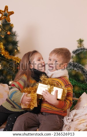 Sister and brother sharing secrets under Christmas tree
