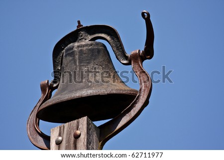 Large Old Bell nailed on top of the wooden post.