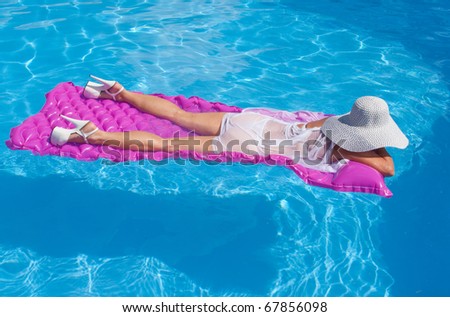 Woman wearing high heels floating on a pink float.