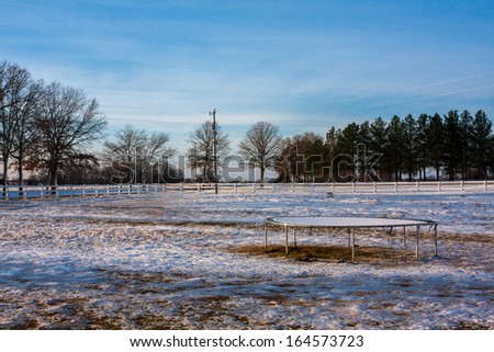 Country landscape with fresh snow covering the trampoline and ground