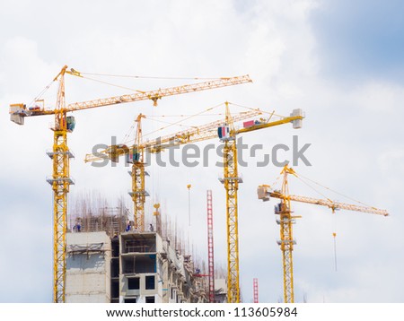 tower crane hoisting concrete blocks load on the top of building under construction