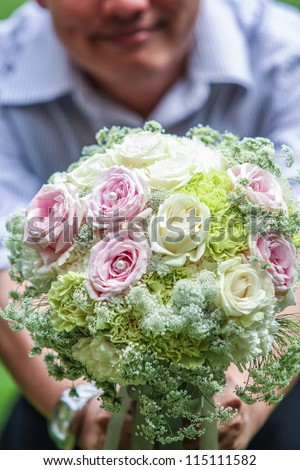 Asian man holing flower, giving flower pose of a man with smile on his face