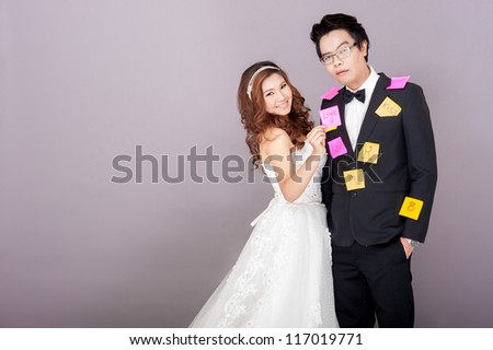Bride putting post note on the groom with smile on her face while groom make his expression of confuse and surprise