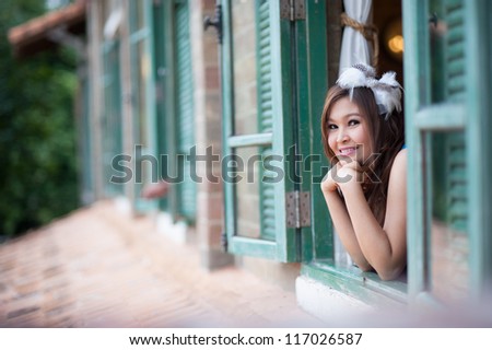 Asian female in the window looking at the camera after take her relax time looking at the view out the window