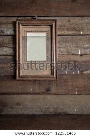Old wooden frame hanging on wooden wall with broken glass