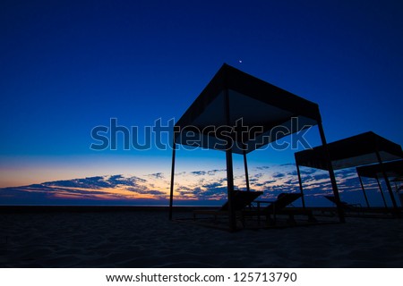 Twilight morning by the beach with beach tent and bench in silhouette