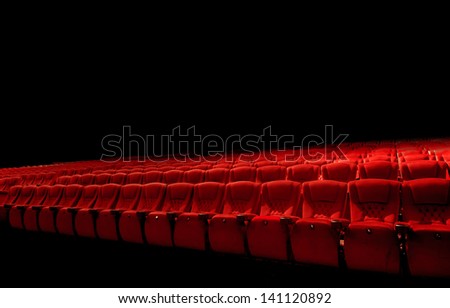 Rows of red movie theater seats in dark surrounding