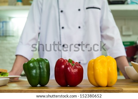 three color sweet peppers as main subject with background of chef in uniform