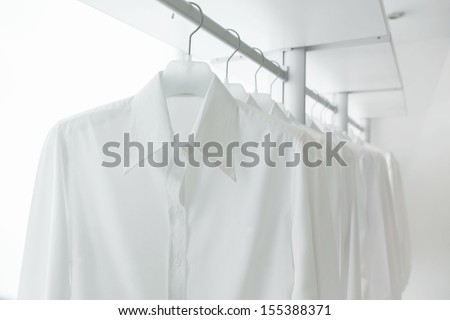 white shirts hanging on rack in built-in cupboard