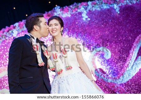 Thai wedding on purple stage when the groom gives his bride a kiss on her cheek