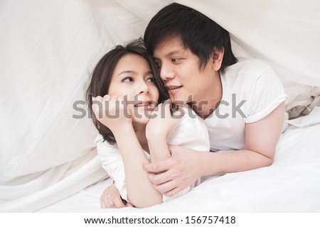 Young Asian couple under blanket in the morning