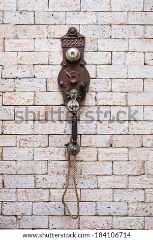old telephone hanging on brick wall