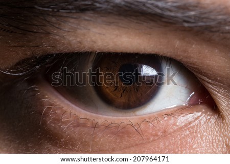 super macro shot of asian male\'s eye. Texture of the dark eye is visible