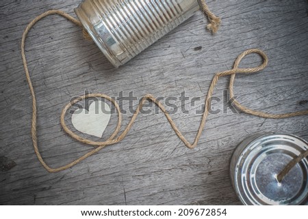 tins telephone with rope connecting shaped the word love on wooden background