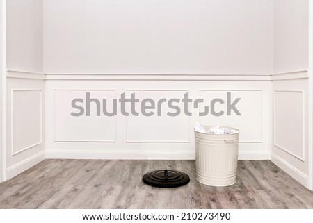 room with trash bin filled with papers on wooden floor