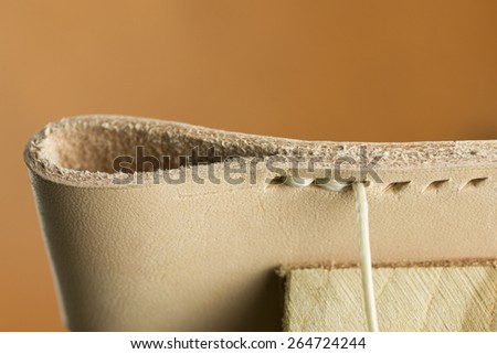 handmade sewing leather with thread and hands pulling it