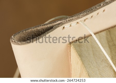 handmade sewing leather with thread and hands pulling it