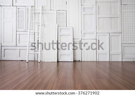 White painted window hinge on wall with white ladder on wooden floor
