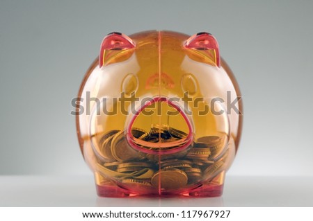 orange translucent piggy bank with coins inside
