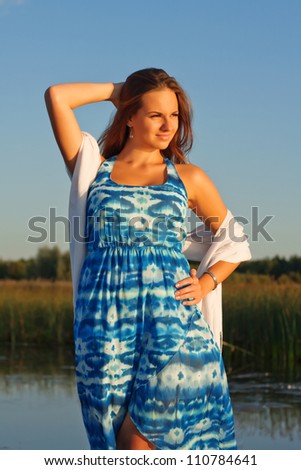 Nice portrait of brunette lady in nice blue dress posing in front of beautiful field