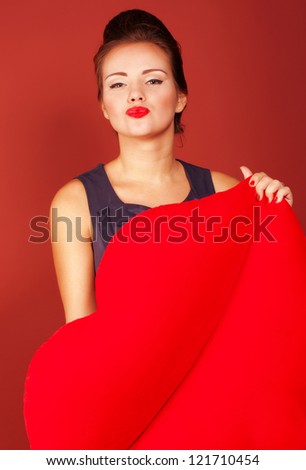 Wonderful girl with big red toy heart give you a kiss