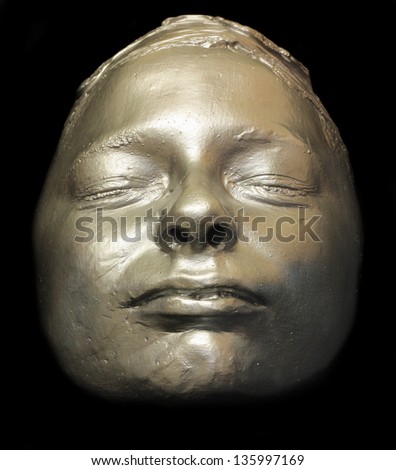 Silver painted plaster cast mold of childs face on black background