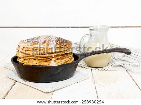 Pancakes with condensed milk on the wooden background