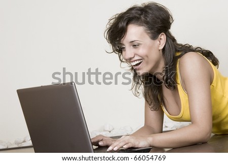 laughing young beautiful girl works with the laptop lying on the floor