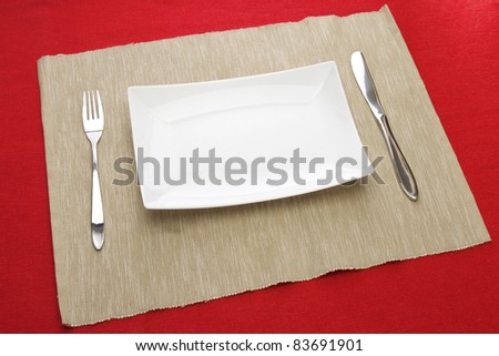 white plate fork and knife on red table