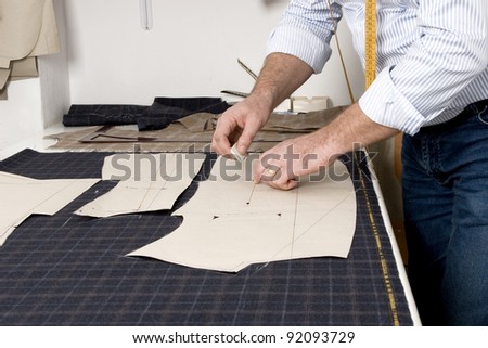 Tailor at work, drawing line on fabric with chalk