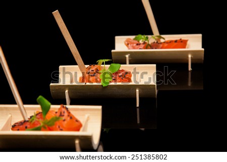 Raw salmon sushi meat cubes on  black background.
