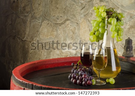 Still life with ripe grapes, wine glasses and wine bottles in old cellar