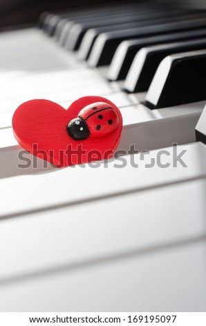 Red heart with ladybug ornament on piano keyboard