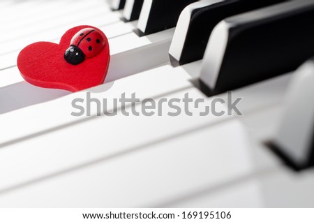 Red heart ornament with ladybug on piano keyboard