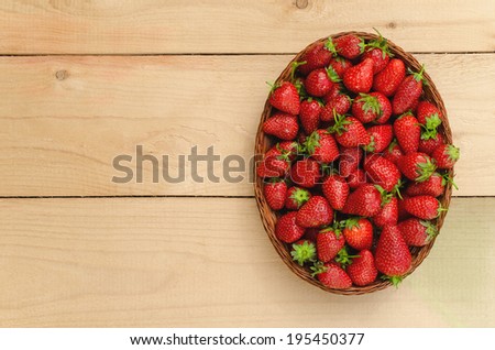 Strawberry in basket on wooden table - birds eye view
