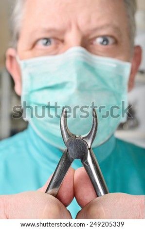 Dental pliers in hands of scary dentist. Selective focus on pliers