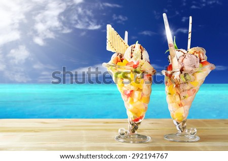 Two cups of fruit salad with sea in the background