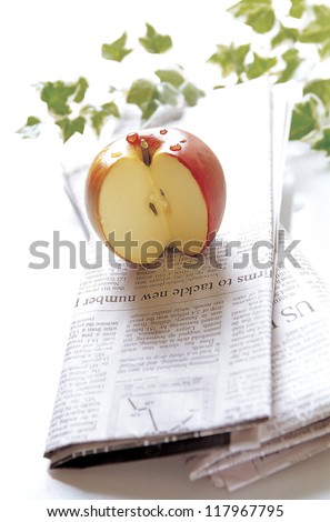 a cut apple on newspapers with green leafs around